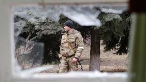 Un militar, visto a través de un cristal roto en una escuela atacada por los bombardeos rusos en la ciudad de Horlivka, en la región de Donetsk.
