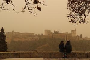 Dos personas observan la Alhambra de Granada desde el Mirador de San Nicolás durante el episodio de calima del pasado mes de marzo, uno de los más intensos registrados en las últimas décadas.
