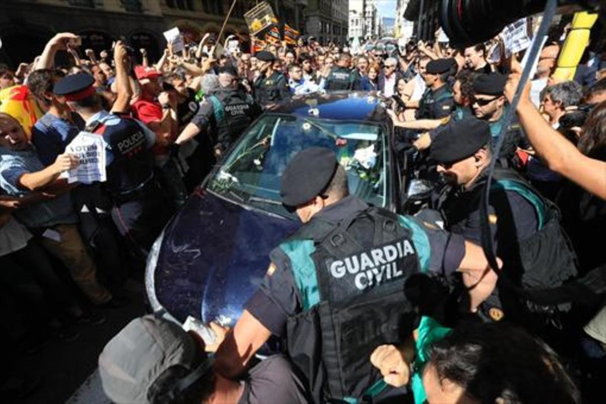 Mossos ayudan a guardias civiles a salir de una concentración de protesta ante la Conselleria d’Afers Exteriors.