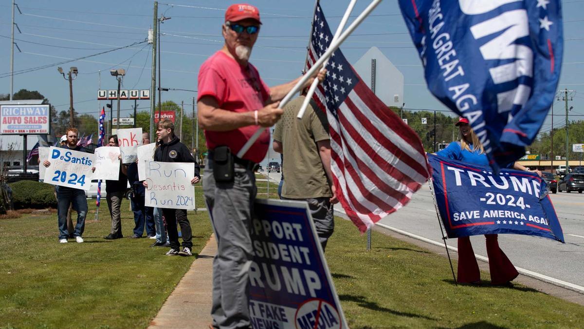 Los partidarios del expresidente de EE. UU., Donald Trump, y los partidarios del gobernador de Florida, Ron DeSantis, sostienen carteles en apoyo de su candidato.