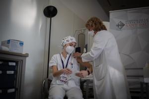Una sanitaria inyecta una vacuna a una trabajadora del Hospital de la Santa Creu i Sant Pau de Barcelona.