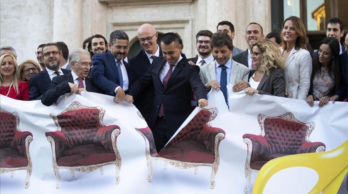 Di Maio (centro) y otros políticos rasgan una pancarta ilustrativa sobre la reforma para reducir el número de parlamentarios en Italia.  
