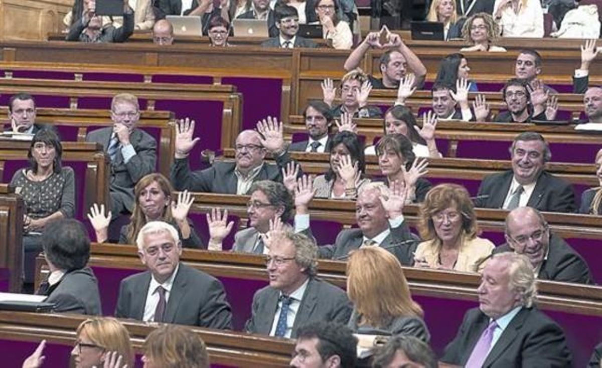 Los diputados del PP alzan las manos para mostrar que no pulsan ningún botón en la votación. Al fondo, Fernández (CUP) hace el símbolo feminista. Los diputados del PP alzan las manos para mostrar que no pulsan ningún botón en la votación. Al fondo, Fernández (CUP) hace el símbolo feminista.