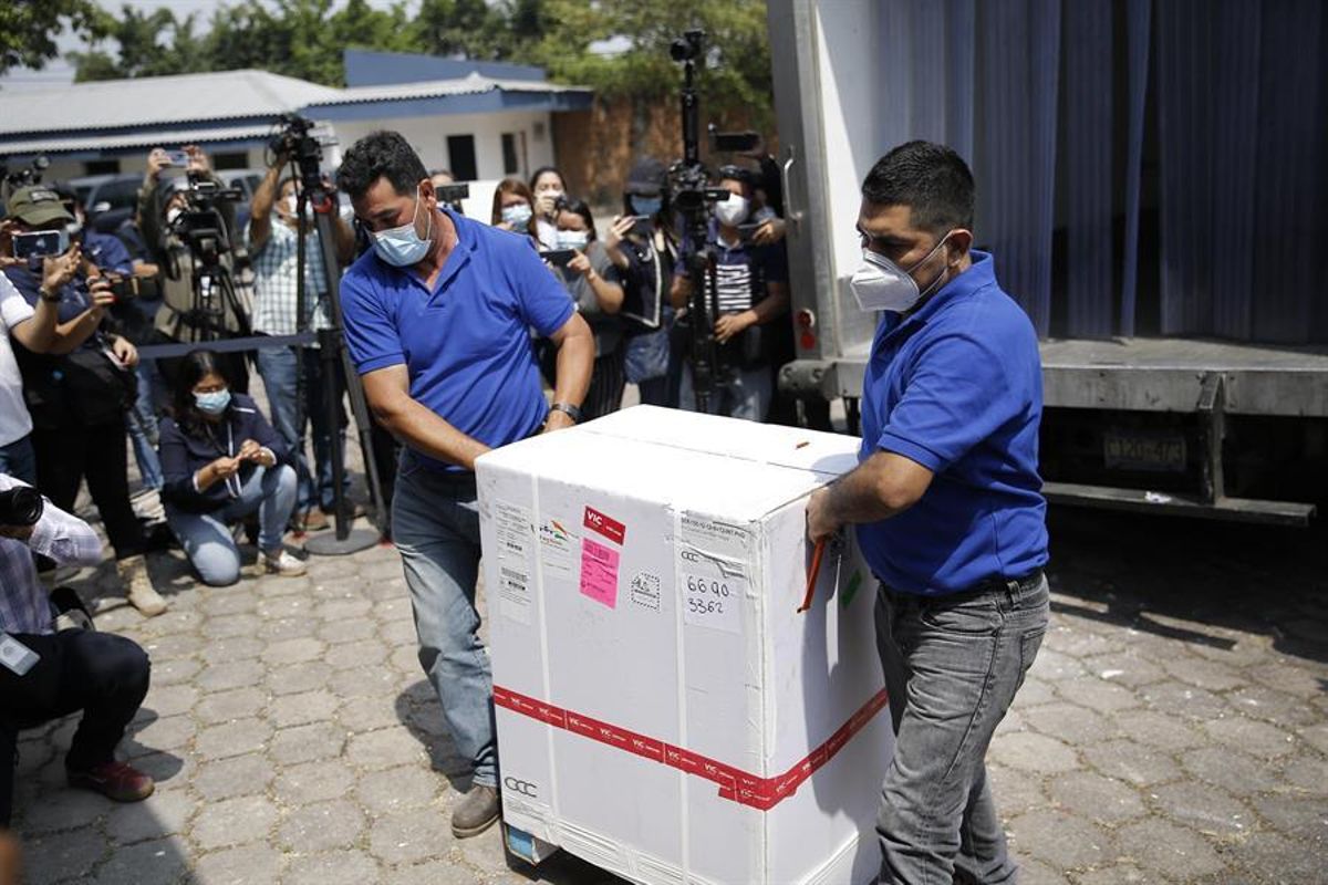 Dos hombres bajan de un camión una caja que contiene dosis de las vacunas contra el covid-19. Dos hombres bajan de un camión una caja que contiene dosis de las vacunas contra el covid-19.