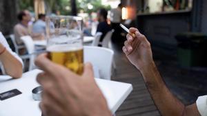 Una persona sostiene un cigarrillo en una terraza.