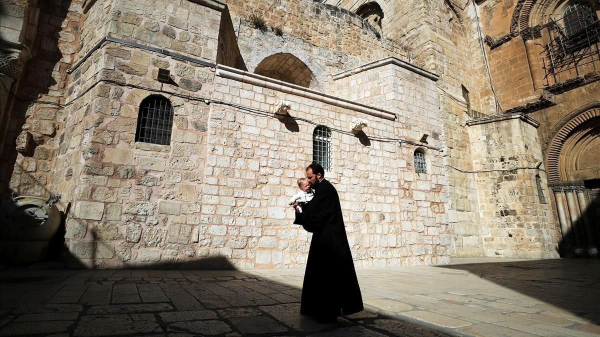 Un sacerdote cristiano camina con un niño en brazos por la plaza de la iglesia del Santo Sepulcro, este domingo en Jerusalén. Un sacerdote cristiano camina con un niño en brazos por la plaza de la iglesia del Santo Sepulcro, este domingo en Jerusalén.