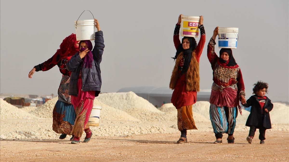 Mujeres sirias cuyas familiares han huido de los bombardeos en Idleb y la zona de Alepo cargan con cubos improvisados de agua, en un campamento de desplazados cerca de Bab al-Hawa, junto a la frontera sirioturca, el 22 de enero. Mujeres sirias cuyas familiares han huido de los bombardeos en Idleb y la zona de Alepo cargan con cubos improvisados de agua, en un campamento de desplazados cerca de Bab al-Hawa, junto a la frontera sirioturca, el 22 de enero.