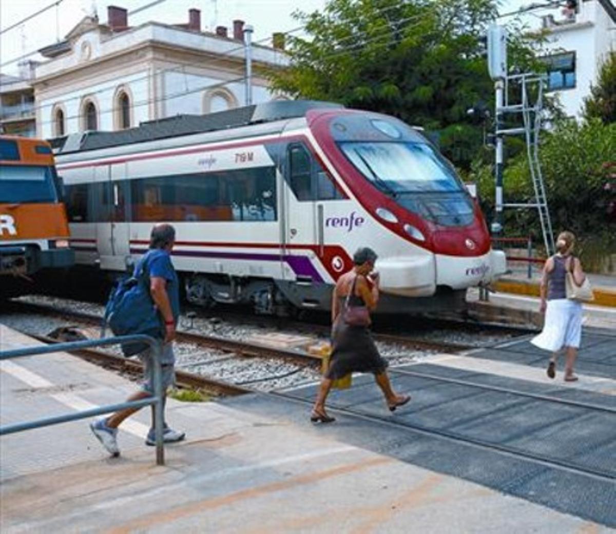 Viajeros atraviesan las vías de tren por el paso para peatones en la estación de Sant Pol. Viajeros atraviesan las vías de tren por el paso para peatones en la estación de Sant Pol.