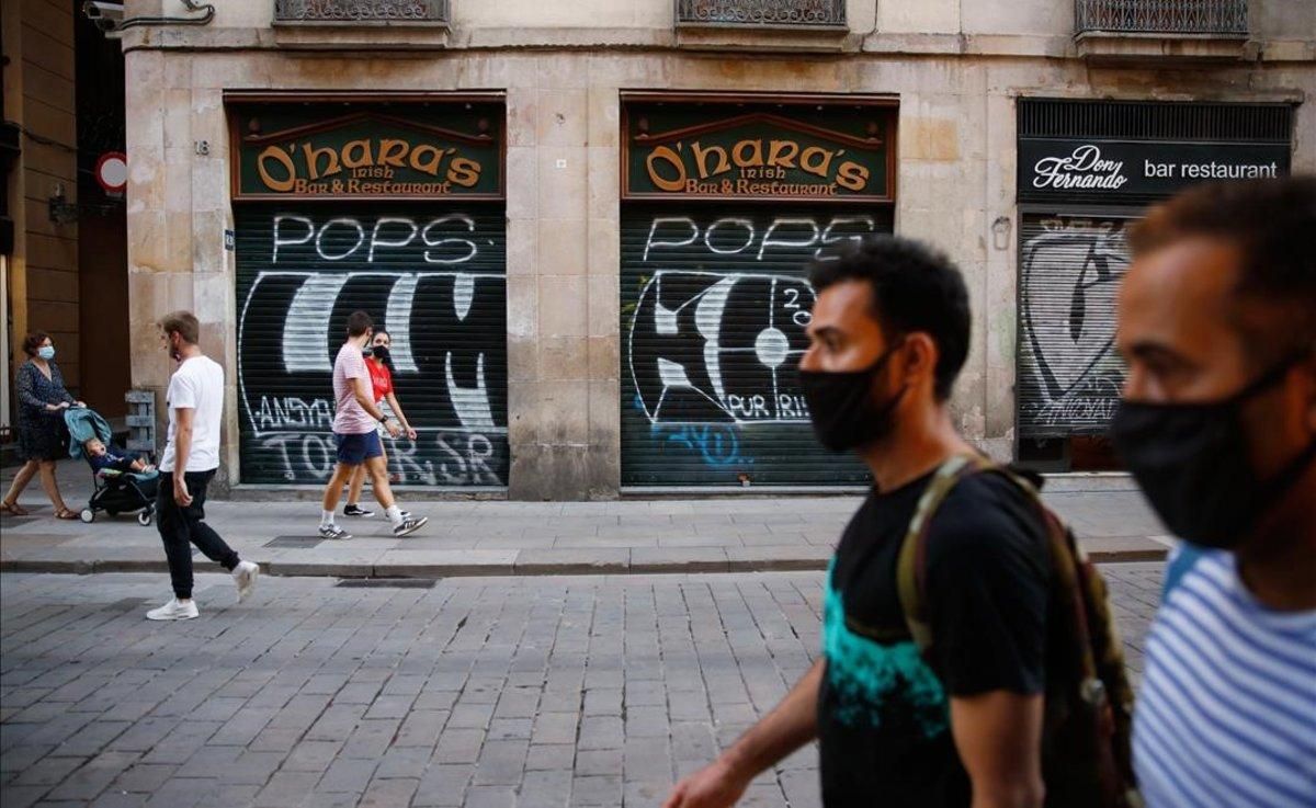Dos hombres con mascarilla, en una calle céntrica de Barcelona con los comercios cerrados. Dos hombres con mascarilla, en una calle céntrica de Barcelona con los comercios cerrados.