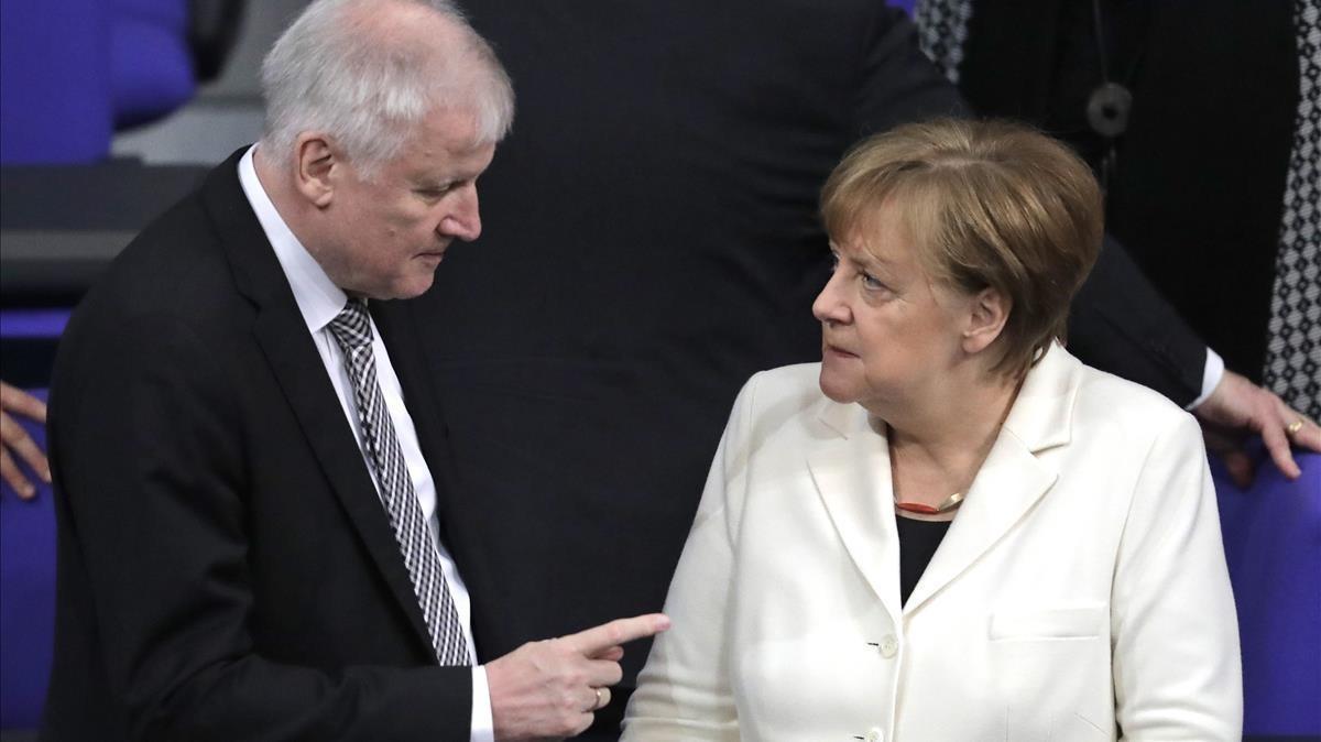Seehofer (izq) habla con Merkel en el Parlamento alemán, en Berlín, el 14 de marzo.
