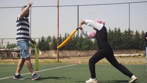 Aya, de 13 años, practica su push mientras la corrige Mohammed Kheir, entrenador y jefe del programa de críquet de Alsam.