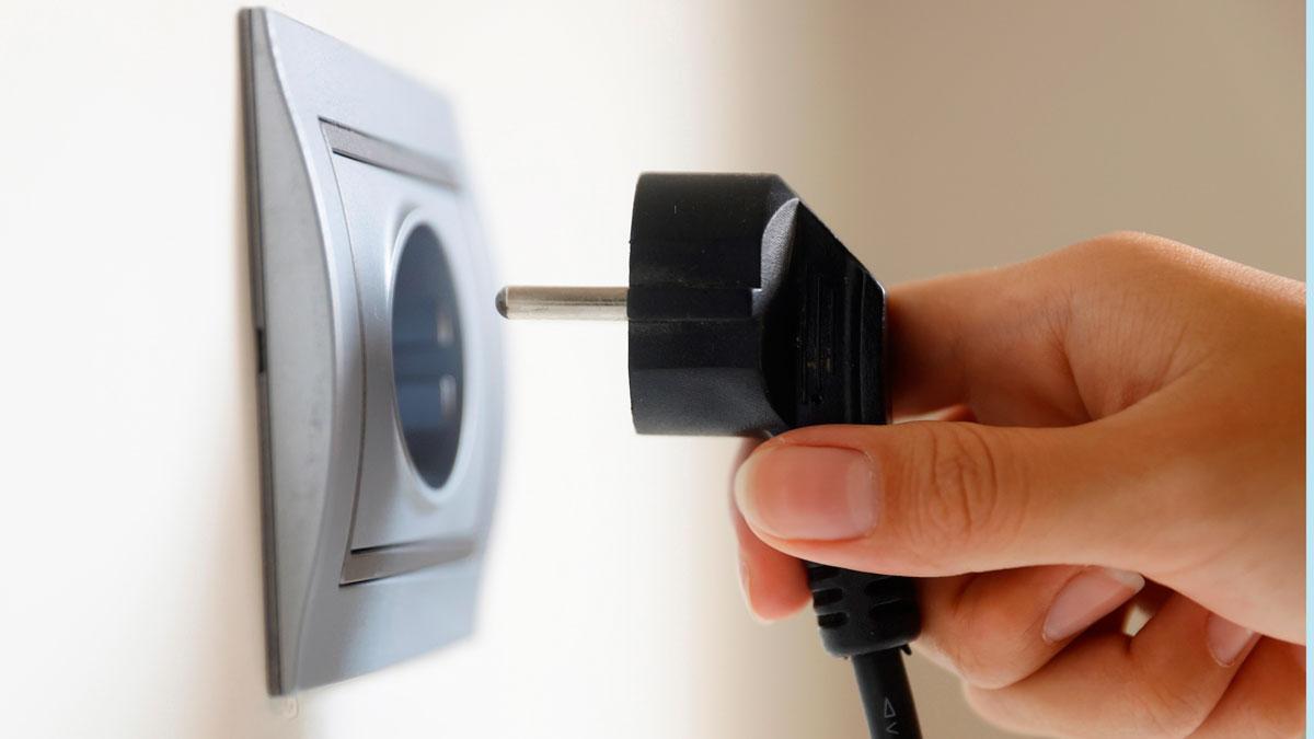 Un usuario conecta un enchufe a la corriente eléctrica.