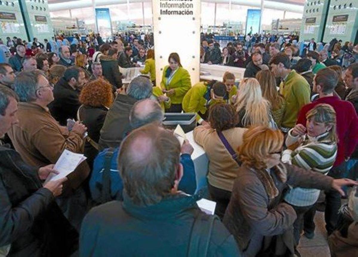 Colas de pasajeros ante el mostrador de información de AENA en la T-1 del aeropuerto de El Prat, ayer.