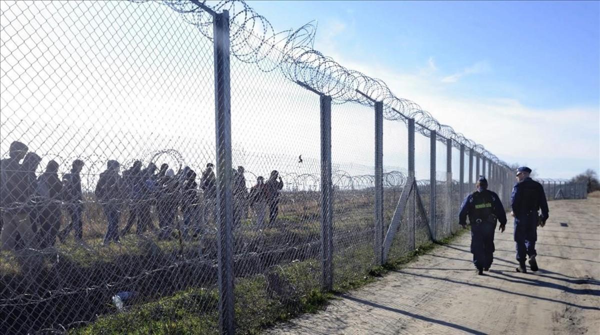 Policías húngaros vigilan a refugiados tras una valla temporal en la frontera con Serbia, cerca de Morahalom, el 22 de febrero del 2016.