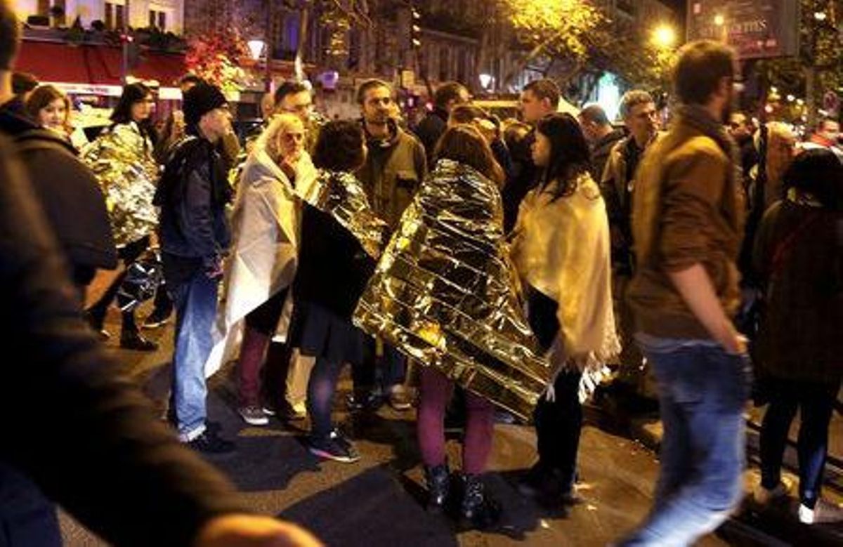 Las personas se calientan bajo mantas térmicas de protección tras ser liberados de la sala de conciertos. Las personas se calientan bajo mantas térmicas de protección tras ser liberados de la sala de conciertos.