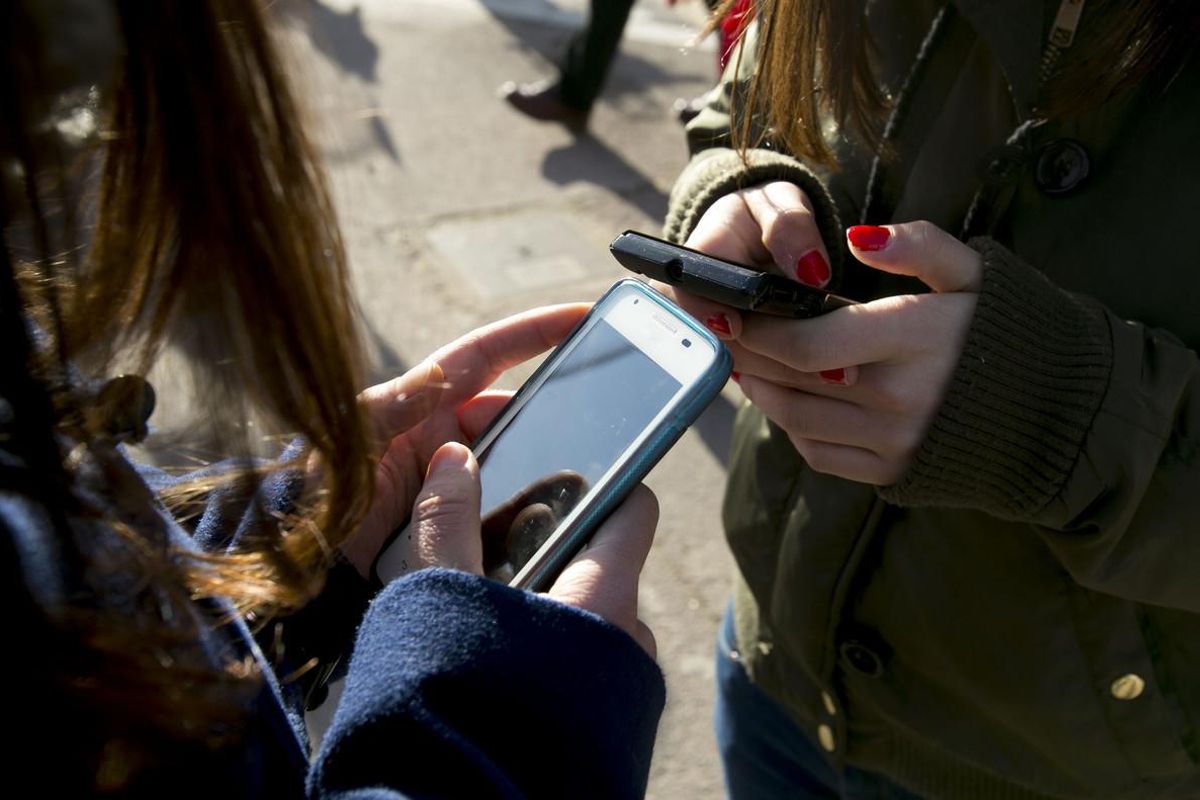 Jóvenes utilizando el móvil a la salida de su instituto. Jóvenes utilizando el móvil a la salida de su instituto.