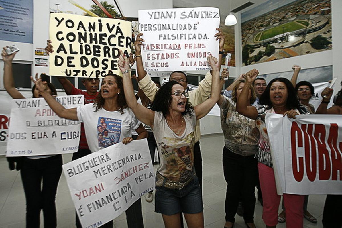Simpatizantes del régimen cubano gritan consignas y muestran carteles durante la visita de la cubana Yoani Sánchez a Brasil.