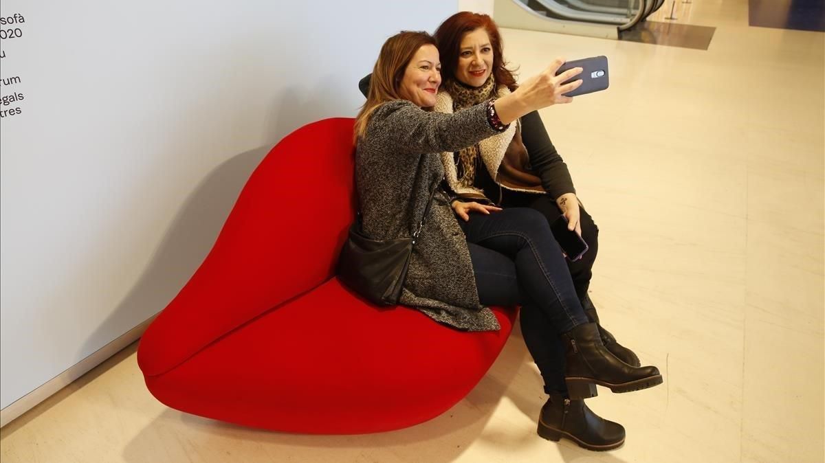 Dos visitantes de la exposición ’Objetos de deseo’ de CaixaFòrum se fotografían en el acceso a la misma. Dos visitantes de la exposición ’Objetos de deseo’ de CaixaFòrum se fotografían en el acceso a la misma.