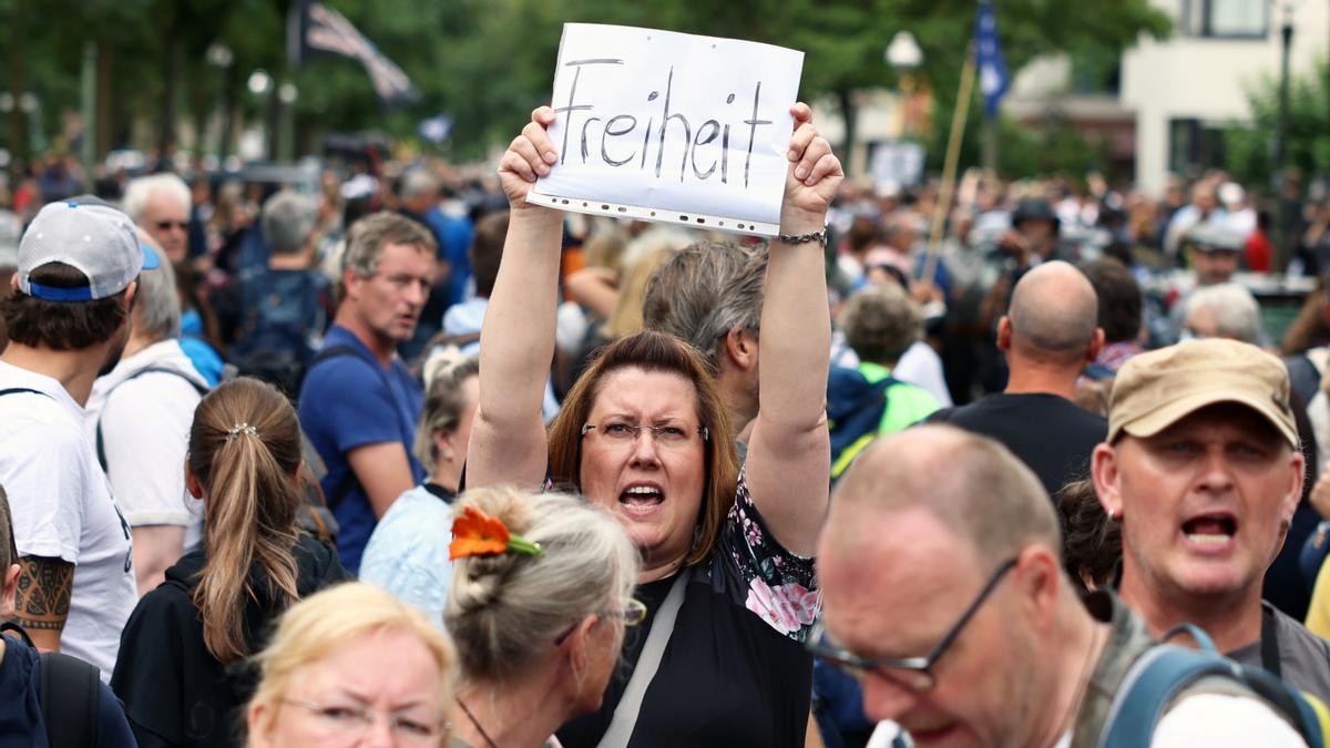 Una manifestante en Berlín protesta contra las restricciones y alza una pancarta que pone libertad. Una manifestante en Berlín protesta contra las restricciones y alza una pancarta que pone libertad.