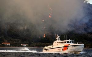 Un barco de la Guardia Costera huye de las llamas en Turquía.
