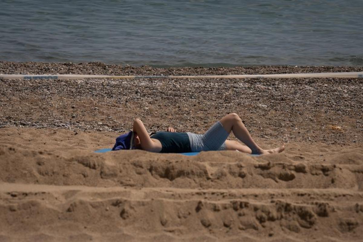 Una mujer toma el sol en una playa catalana durante el episodio de altas temperaturas de este mes de abril.