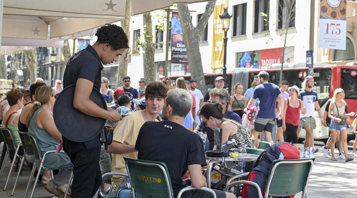 Un camarero atiende a unos clientes en una terraza de Barcelona.