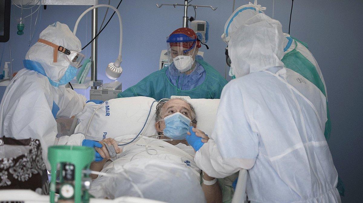 Varios sanitarios atienden a un enfermo con coronavirus en la uci de un hospital.