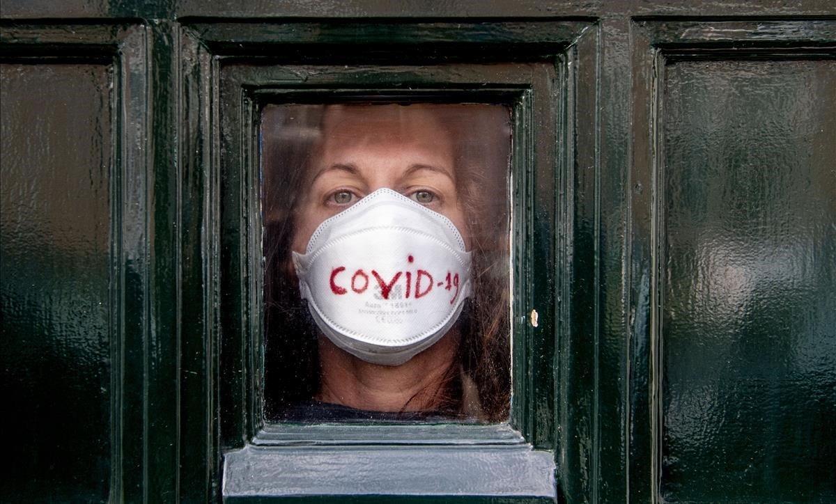 Una mujer mira al exterior desde la puerta de su casa,  en La Haya, donde permanece en cuarentena por el coronavirus. 
