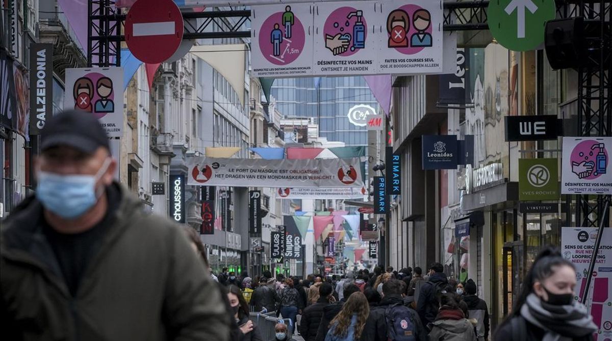 Paseantes con mascarilla por una de las principales calles de compras en Bruselas. Paseantes con mascarilla por una de las principales calles de compras en Bruselas.