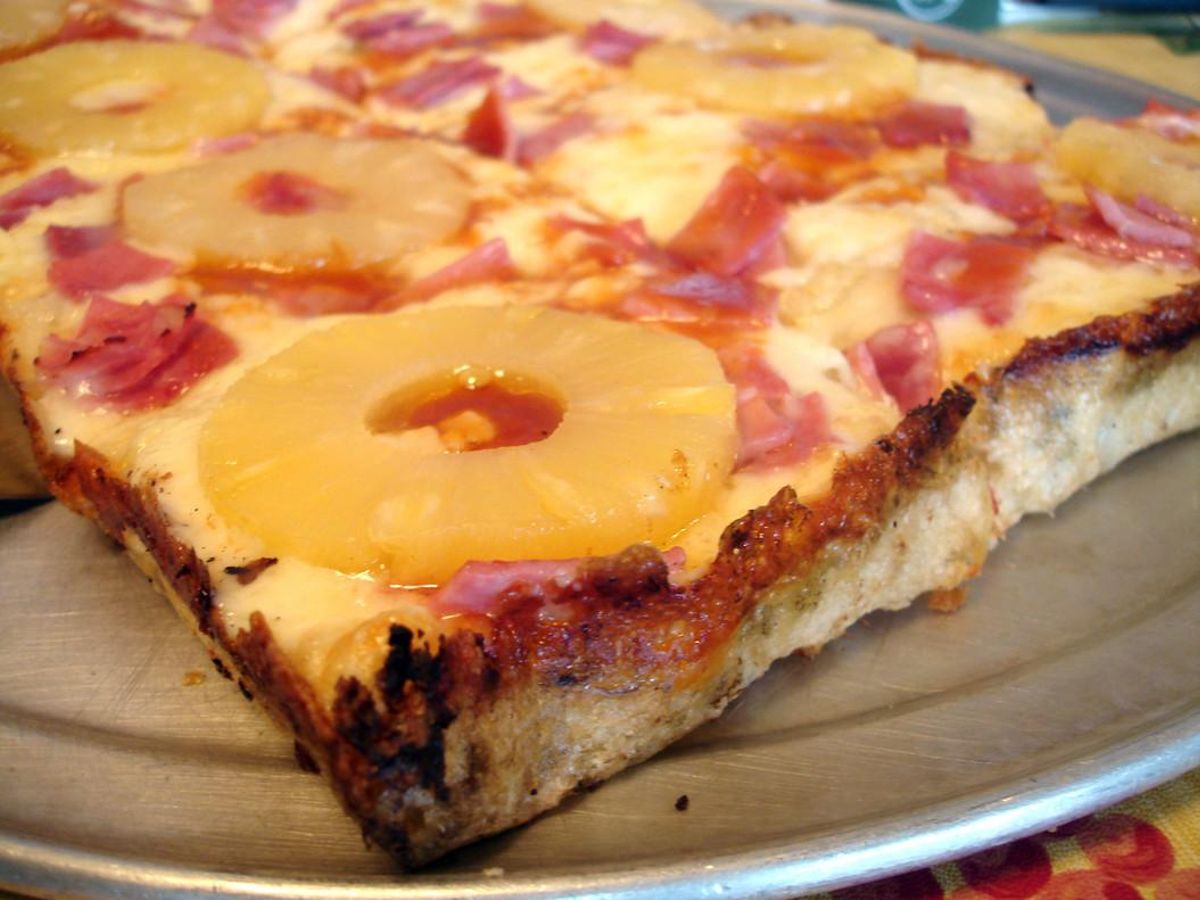 Una porción de pizza hawaiana, con rodajas de piña enteras. Una porción de pizza hawaiana, con rodajas de piña enteras.