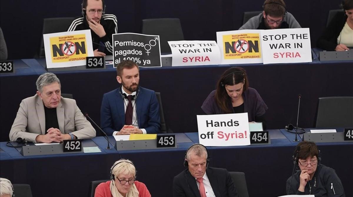 Europarlamentarios muestran carteles contrarios al ataque a las instalaciones del régimen de Asad.