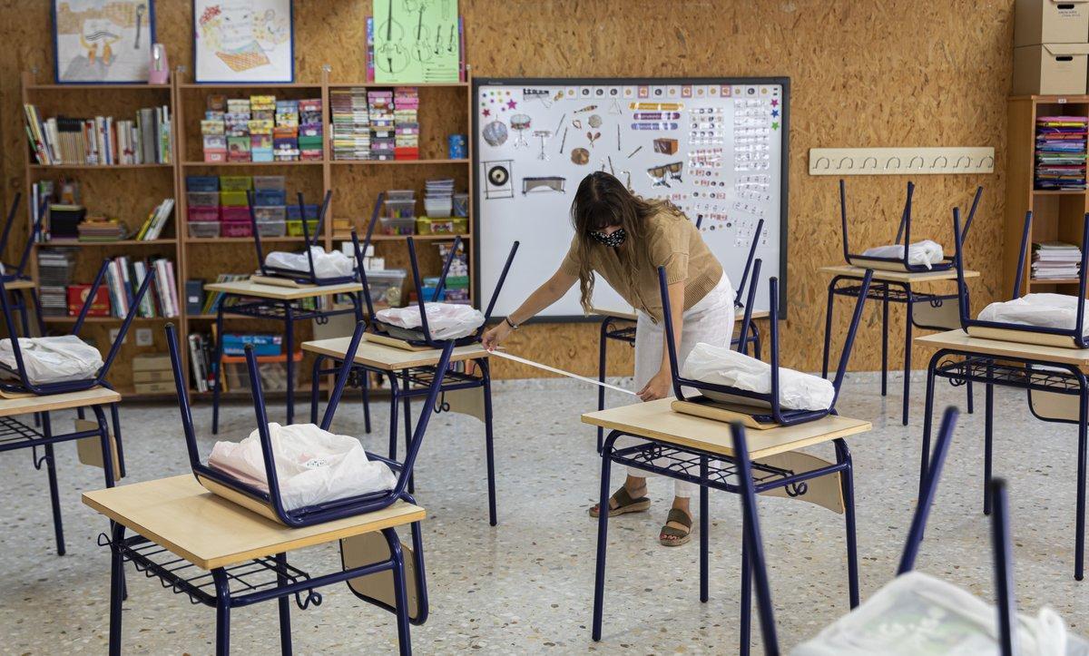 Una profesora mide la distancia de separación en un aula.