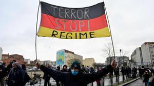 Un manifestante antivacunas muestra una bandera alemana en la que se puede leer Stop al régimen de terror durante una protesta en Berlín, el pasado 26 de enero.