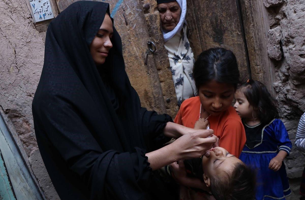 Unos trabajadores sanitarios visitan un hogar para administrar una vacuna contra la polio a los niños en la ciudad de Herat (Afganistan)