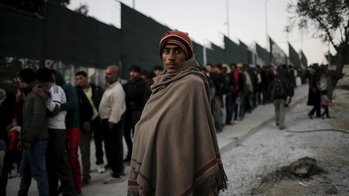 Un refugiado, cubierto con una manta, junto a la cola de distribución de comida en el campo de Moria, en Lesbos, en una imagen de archivo. Un refugiado, cubierto con una manta, junto a la cola de distribución de comida en el campo de Moria, en Lesbos, en una imagen de archivo.