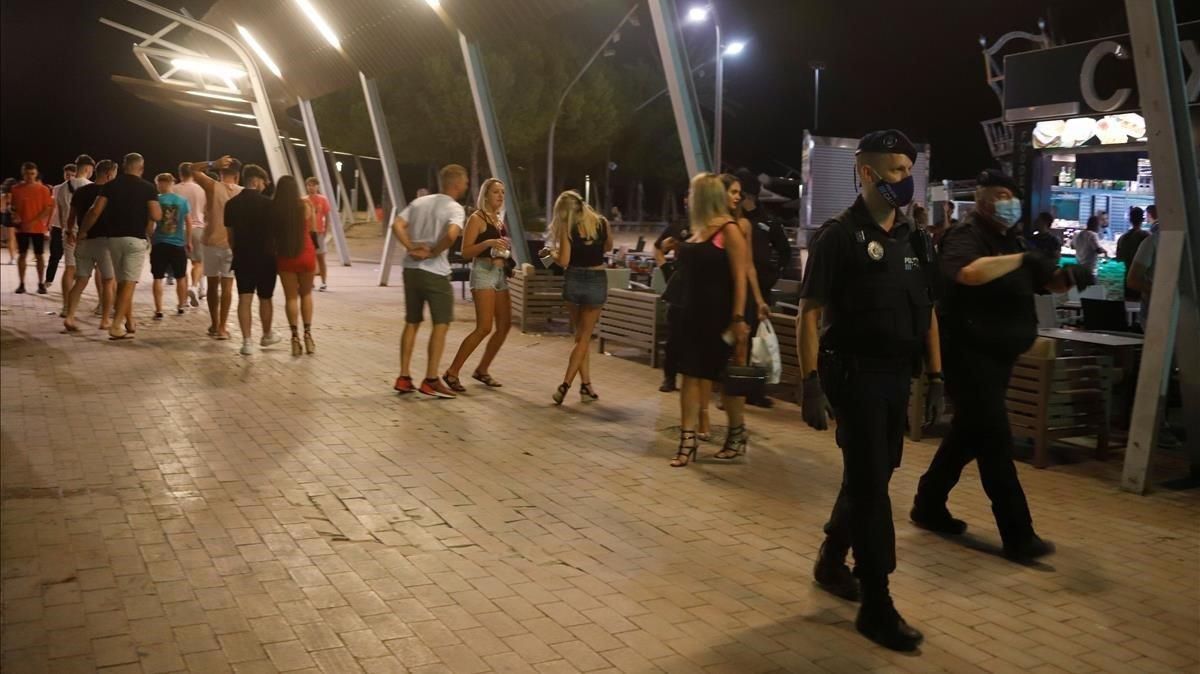 La Policía pasa delante de jóvenes sin msacarilla en Magaluf. La Policía pasa delante de jóvenes sin msacarilla en Magaluf.