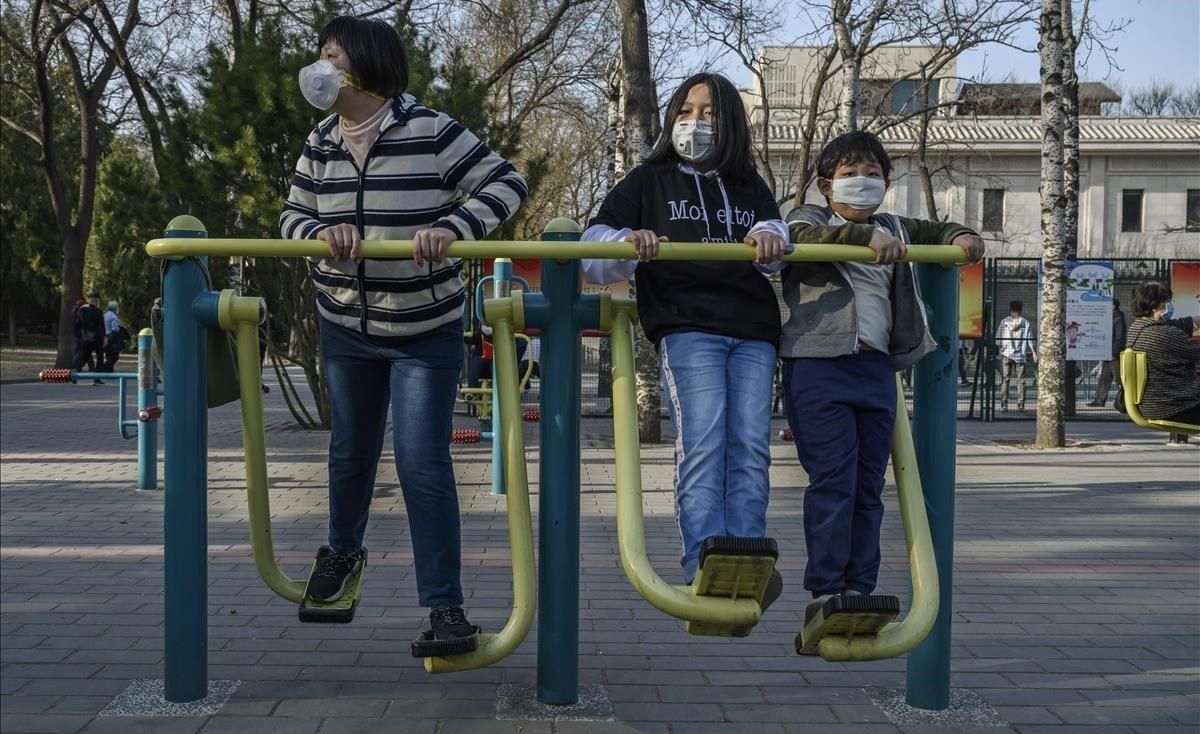 Una familia china se protege con máscaras mientras hace ejercicio en un parque de Pekín, este domingo. Una familia china se protege con máscaras mientras hace ejercicio en un parque de Pekín, este domingo.