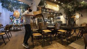 Un hombre coloca sillas en el interior de un bar en el Gòtic de Barcelona, este jueves.