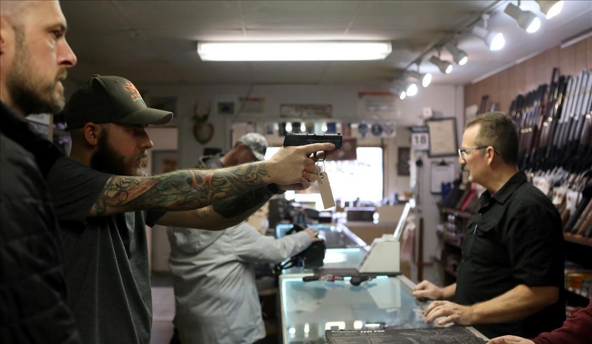 Un hombre sostiene una pistola en una tienda de armas en Cheyenne, Wyoming, ante el temor al caos por la propagación del coronavirus.