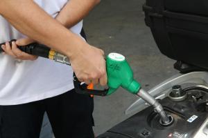 Un empleado de una gasolinera rellena el depósito de una moto, en Barcelona. 