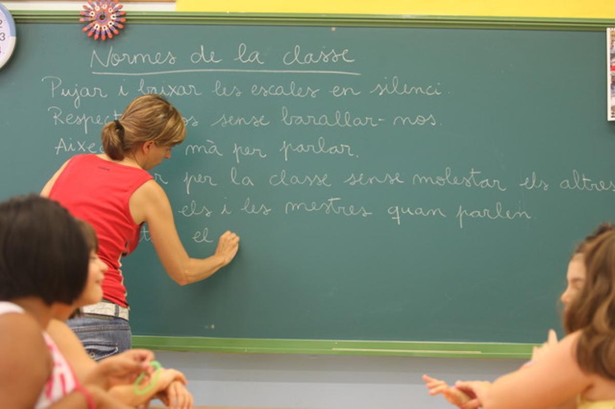 Una profesora escribe las normas de clase, hoy, en el colegio La Sedeta.