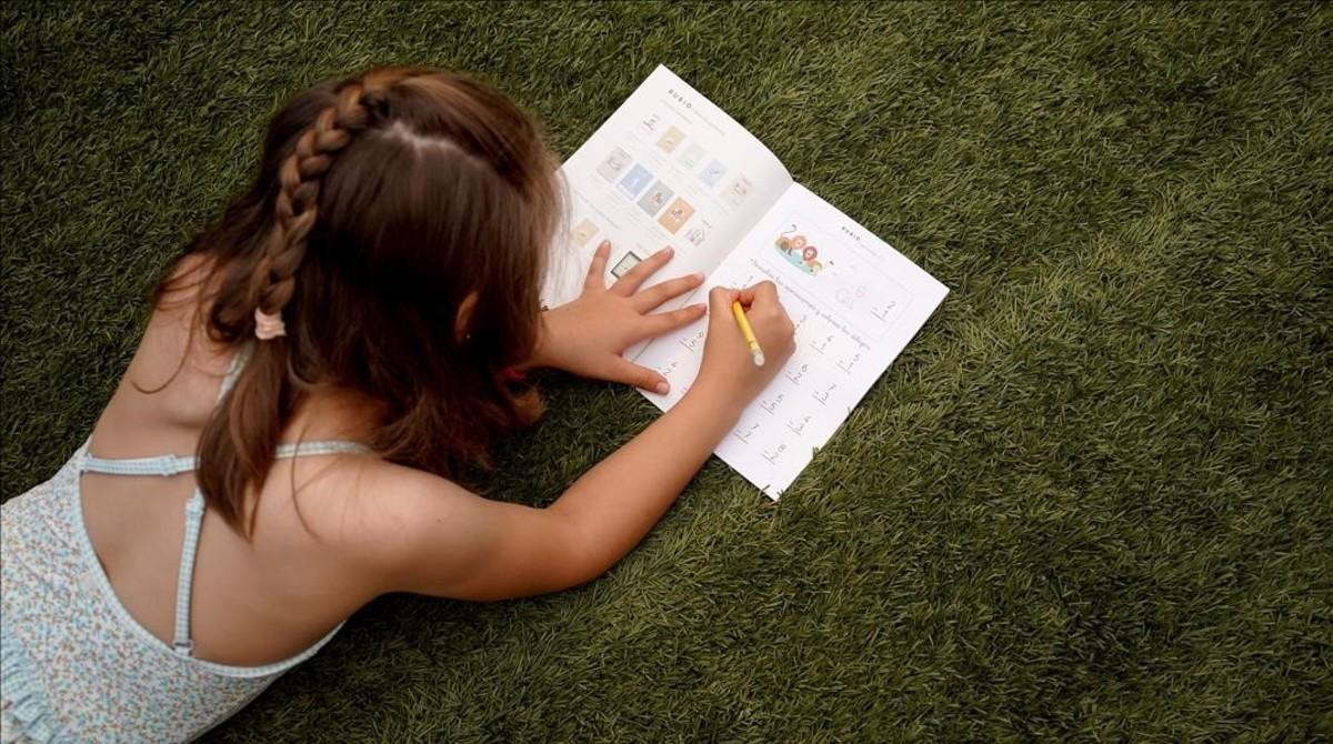 Una niña de siete años estrena sus vacaciones, el viernes en Madrid, haciendo ejercicios en un cuaderno Rubio.