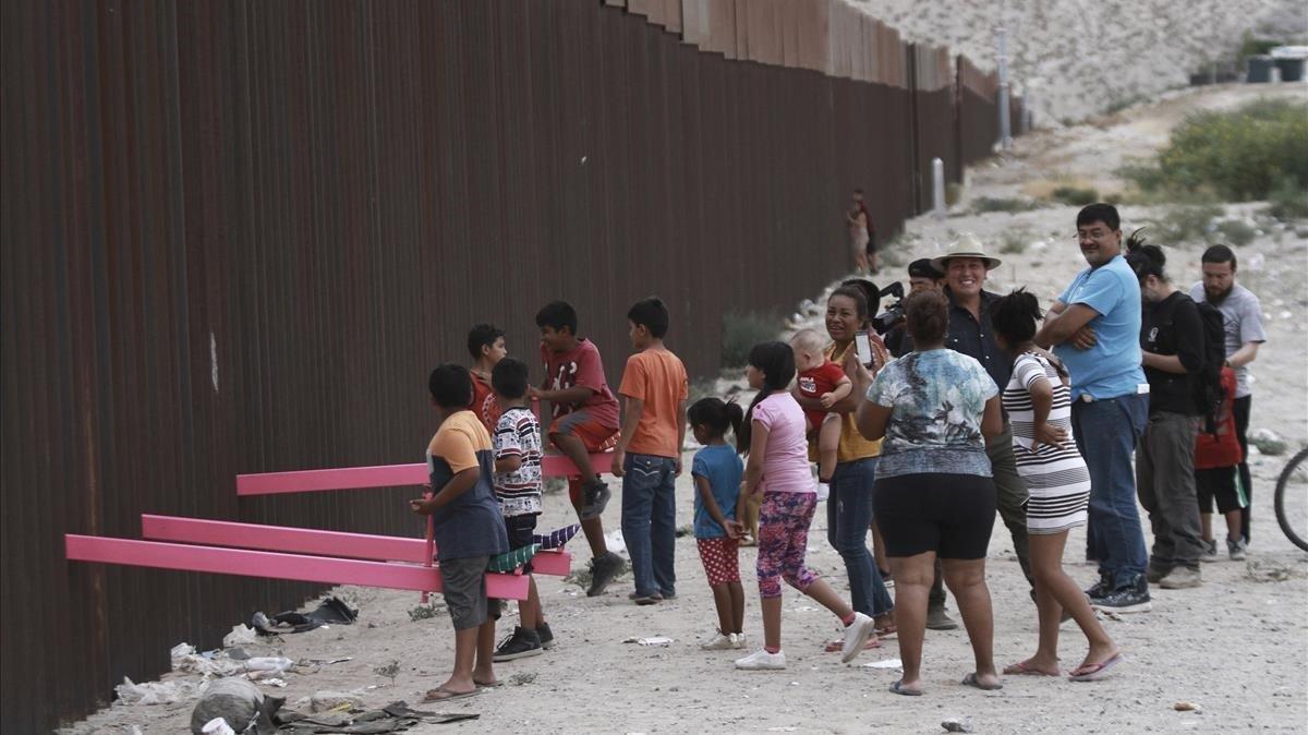 Niños juegan en un balancín situado en el muro de México a su paso por Ciudad Juarez.