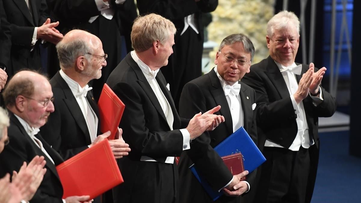 El Nobel de Literatura del 2017, Kazuo Ishiguro (el segundo por la derecha), flanqueado, de izquierda a derecha, por los galardonados en Medicina (Jeffrey Hall, Michael Rosbash y Michael Young) y Economía (Richard Thaler), en la ceremonia de entrega de los premios en Estocolmo. El Nobel de Literatura del 2017, Kazuo Ishiguro (el segundo por la derecha), flanqueado, de izquierda a derecha, por los galardonados en Medicina (Jeffrey Hall, Michael Rosbash y Michael Young) y Economía (Richard Thaler), en la ceremonia de entrega de los premios en Estocolmo.