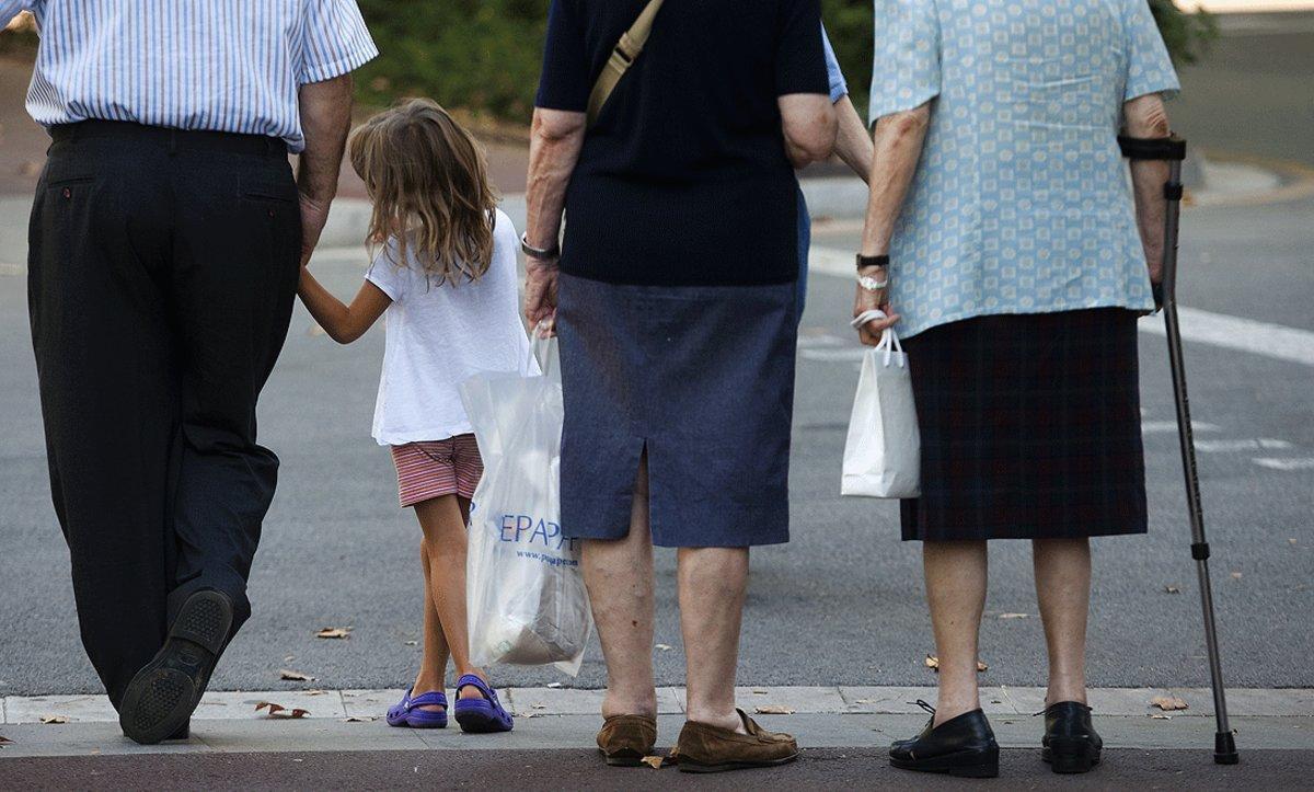 Tres personas de edad avanzada pasean con una niña por Barcelona.