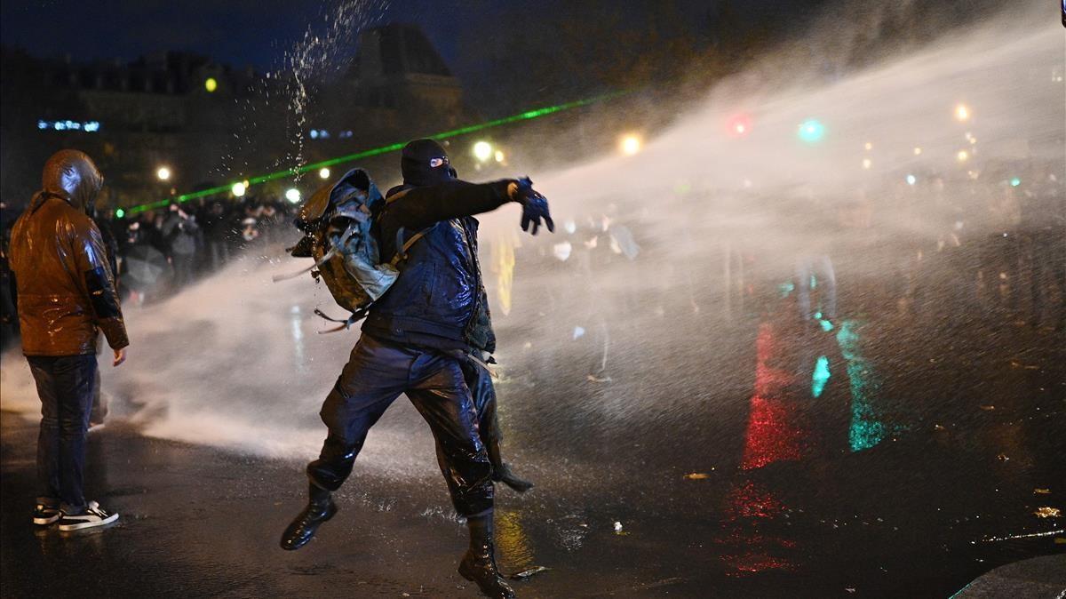 TOPSHOT - A protester throws an object during a demonstration in Paris on december 12 2020 against the global security draft law - It is the third weekend of demonstrations in France during protests against a security bill currently going through French parliament that would restrict publication of pictures showing the faces of police (Photo by Christophe ARCHAMBAULT AFP)