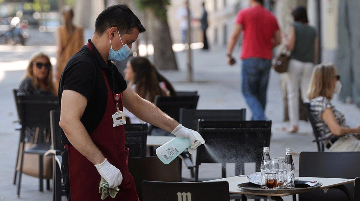 El paro baja en septiembre en 26.329 personas, su mayor descenso desde 1996. En la foto, un camarero desinfecta una mesa de una terraza en Madrid, el pasado 29 de julio.