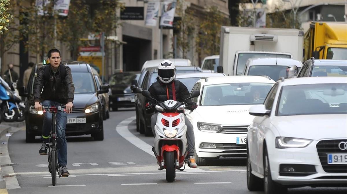 Una bici, una moto y coches, en la calle de Balmes, antes de cruzar la Diagonal.