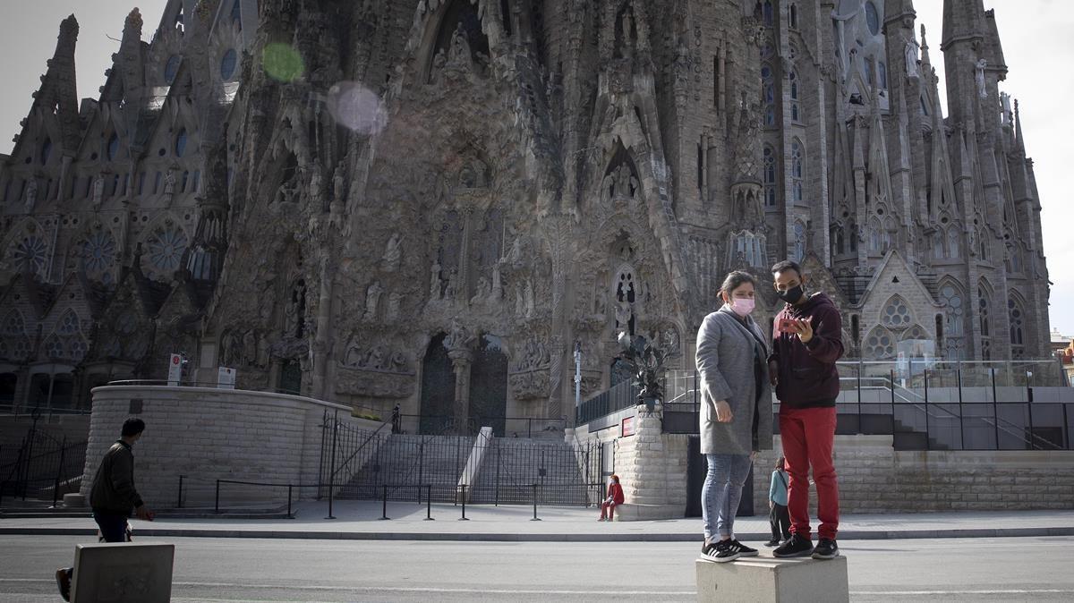 España recibe 18,9 millones de turistas extranjeros en el 2020, 65 millones menos. En la foto, dos turistas junto a la Sagrada Familia, en Barcelona, vacía.