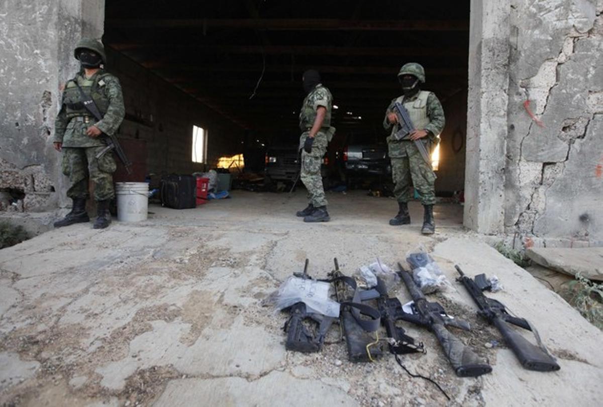  Soldados mexicanos custodian parte del armamento incautado en el campamento de Los Zetas.
